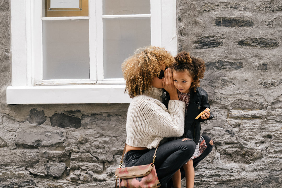 Mother whispering into daughter's ear